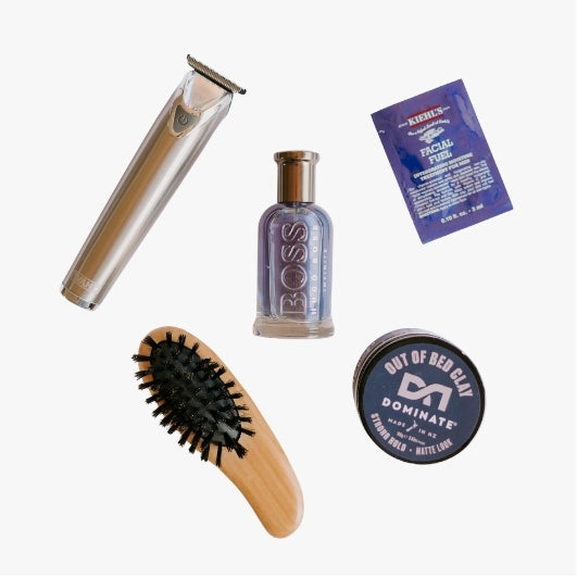 flat lay of mens beauty products for The Beauty Exchange on a neutral background including mens haircare, shaving tools, brushes, cologne and moisturisers 