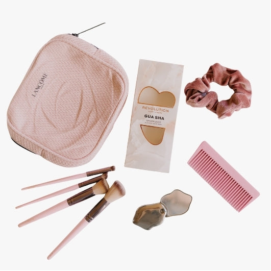 Hands carrying multiple skincare and makeup products for a beauty donation initiative Beauty accessories flat lay featuring makeup brushes, face rollers, gua sha tools, hair accessories, and hair roller