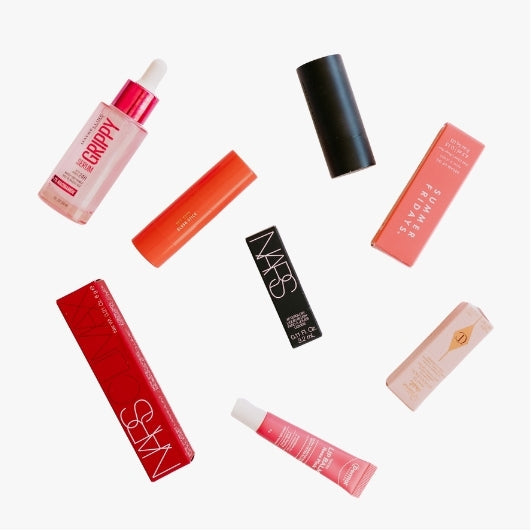 flat lay of makeup products arranged on a light background , assortment of primers concealer, lips, bronzer, blush contour , foundation 